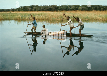 Quattro ragazzi della tribù Libinza in canoa in viaggio di missione Boarding School Ngiri area fluviale Foto Stock