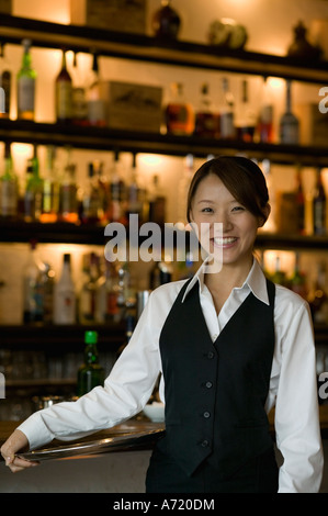 Cameriera in piedi nella parte anteriore del banco bar Foto Stock