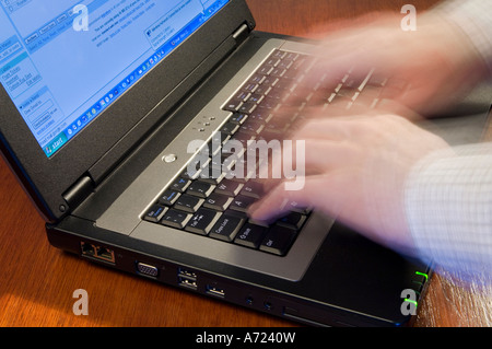 Mani sfocata - suggerendo il movimento - digitando su un laptop computer tastiera Foto Stock