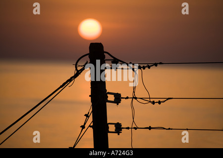 Tramonto dietro il vecchio vestito di stracci in legno palo del telegrafo e fili Creta Foto Stock