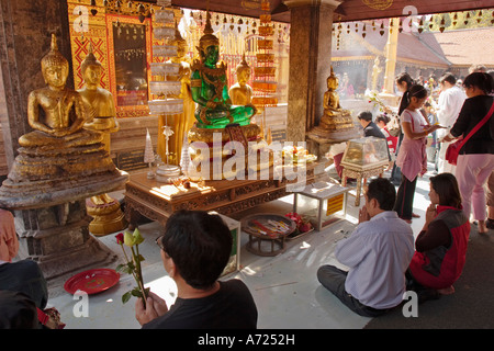 Persone in preghiera davanti all altare con immagine del Buddha di Smeraldo Wat Phrathat Doi Suthep, altamente venerato tempio buddista in Chiang Mai, Thailandia. Foto Stock