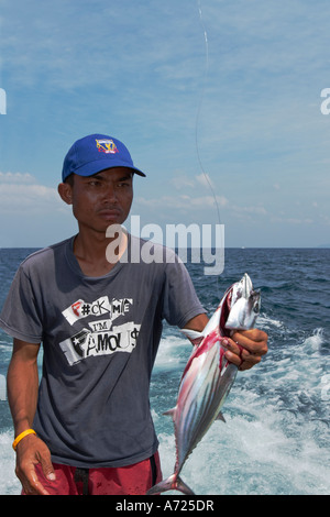 La guida di pesca thailandese tiene in mano un tonno appena pescato. Isola di Phuket, Thailandia. Foto Stock