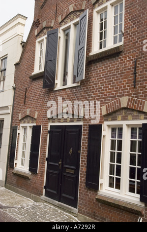 Tradizionale casa in mattoni con finestre a serranda nera a Edam, nell'Olanda settentrionale, caratterizzata da una classica architettura olandese e da una strada acciottolata. Foto Stock