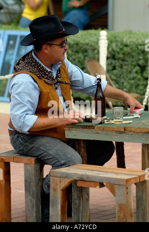 Un uomo che agisce un cowboy carta da gioco intorno a un tavolo Foto Stock