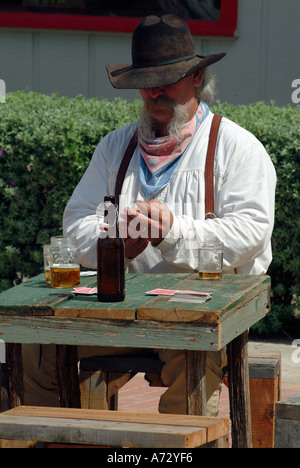 Un uomo che agisce un cowboy carta da gioco intorno a un tavolo Foto Stock