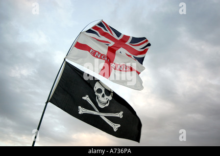 Tre bandiere che sventolano contro un cielo scuro, il Jolly Roger (Teschio e Ossa Croce) Saint Georges, e l'Unione Jack Foto Stock