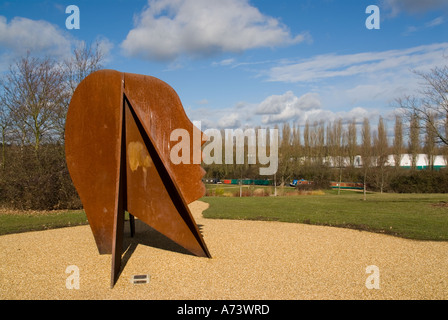 Metallo arrugginito scultura di testa in Campbell Park Milton Keynes Grand Union Canal in background in orizzontale Foto Stock