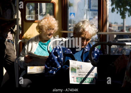 Due donne anziane che viaggiano in un tram a budapest uno guardando attraverso la finestra e gli altri la lettura di un quotidiano gratuito Foto Stock