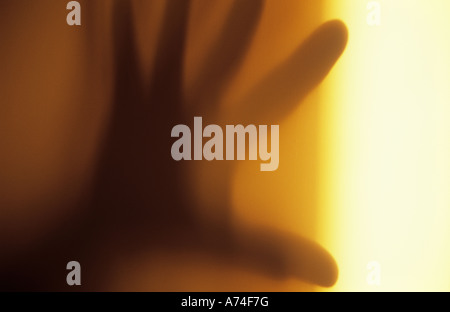 Close up di ombra sul muro di crema nella luce calda della mano che minacciano o circa di sciopero o schiaffo o scongiurare Foto Stock