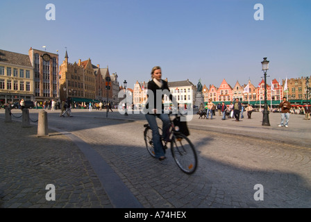 Vista orizzontale di una signora belga in bicicletta lungo il Markt [Market Place] in una giornata di sole a Bruges. Foto Stock