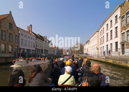 Vista orizzontale di turisti che si godono guidato un viaggio in barca lungo i canali di Bruges in una luminosa giornata di sole. Foto Stock