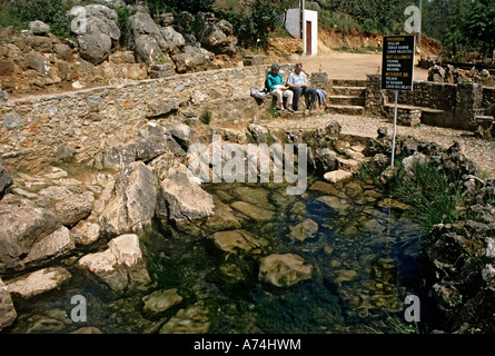 Accoppiare la lettura nella luce del sole a molle con comunicazione multilingue avviso non nuoto pesca o lavaggio Algarve Portogallo Foto Stock