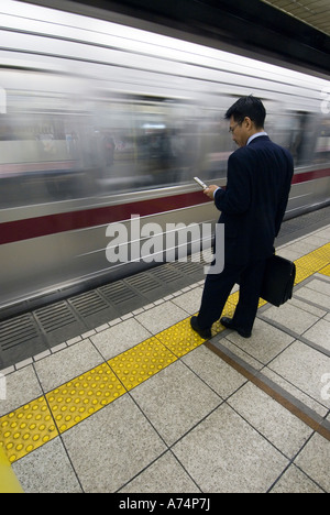 Un imprenditore attende su una piattaforma della metropolitana Tokyo Giappone Foto Stock