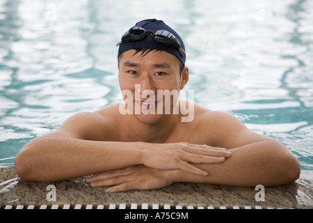 Uomo appoggiato sul bordo della piscina Foto Stock