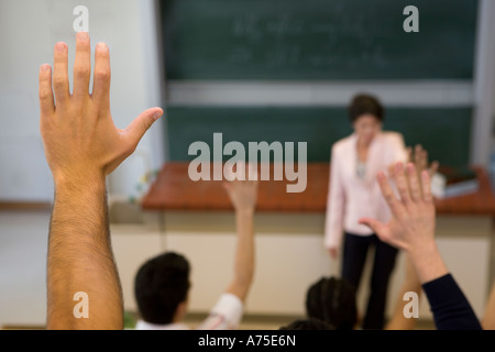 Gli studenti ad alzare la mano in classe Foto Stock