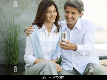 Mid-adulto giovane uomo donna mostra telefono cellulare Foto Stock