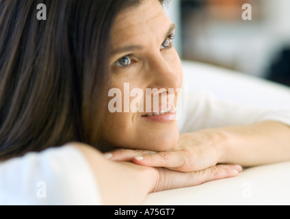 Donna matura appoggiato la testa sulle mani e sorridente, ritratto Foto Stock