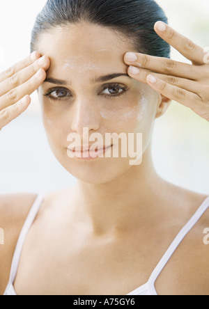 Donna di applicare una crema idratante viso a Foto Stock