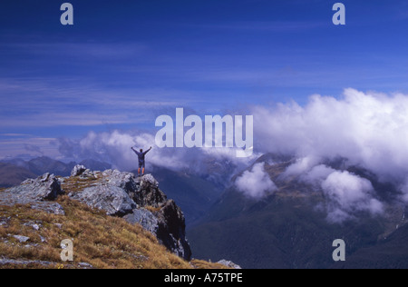 L'uomo trionfante dopo aver raggiunto la cima della collina conica sulla Routeburn Via Isola del Sud della Nuova Zelanda Foto Stock