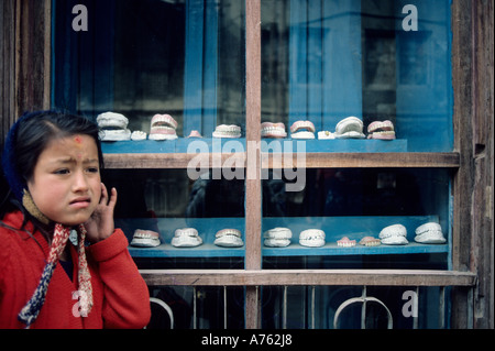 Giovane ragazza locale cercando nel dolore sorge al di fuori del dentista negozio finestra Visualizzazione di denti finti a Kathmandu in Nepal Foto Stock