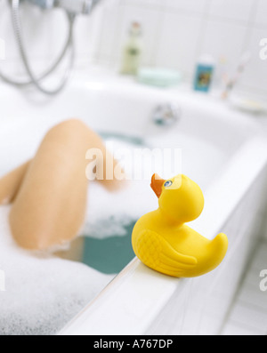 Donna tenendo bagno in vasca con gomma gialla anatra in primo piano Foto Stock