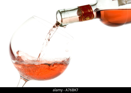 Il vino rosato è versata in un bicchiere grande su un puro sfondo bianco. Foto Stock