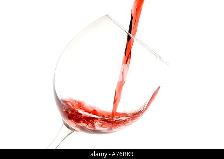 Il vino rosso è versata in un bicchiere grande su un puro sfondo bianco. Foto Stock