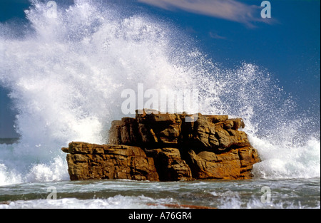 White sea spray che si infrangono sulle rocce contro un cielo blu. Foto Stock