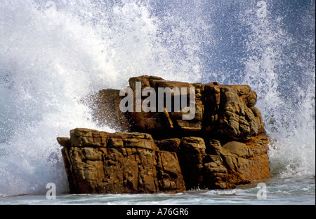 White sea spray che si infrangono sulle rocce contro un cielo blu. Foto Stock