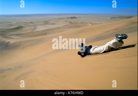 Un boarder di sabbia la discesa delle dune di sabbia della Namibia. Foto Stock