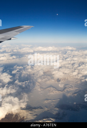 Vista aerea di montagne coperte di neve al tramonto sorvolano la Turchia in inverno con aeromobili ala punta contro il cielo blu e la luna piena Foto Stock