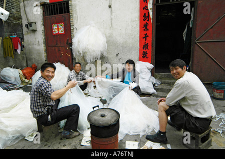 Gli uomini e le donne di smistamento di immondizia di plastica per il riciclaggio, baraccopoli, Cina Foto Stock