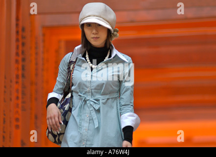 Laccato arancio Torii gate a Fushimi Inari Taisha a Kyoto in Giappone giovani vestiti alla moda donna Foto Stock