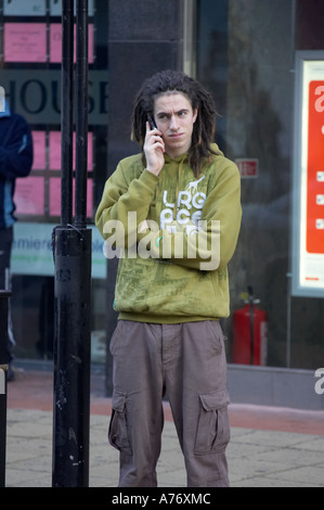 Trendy giovane maschio su telefono cellulare durante lo shopping natalizio a Belfast per la Vigilia di Natale Irlanda del Nord Foto Stock