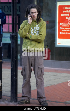 Trendy giovane maschio su telefono cellulare durante lo shopping natalizio a Belfast per la Vigilia di Natale Irlanda del Nord Foto Stock