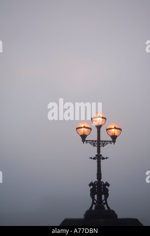 Triple ghisa strada lampada accesa accesa su una serata oscuro Foto Stock