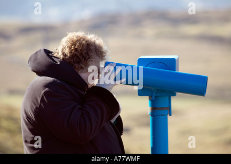 Signora anziana utilizzando il telescopio pubblico rivolto al mare sul Great Orme, Llandudno, Galles del Nord, Regno Unito Foto Stock