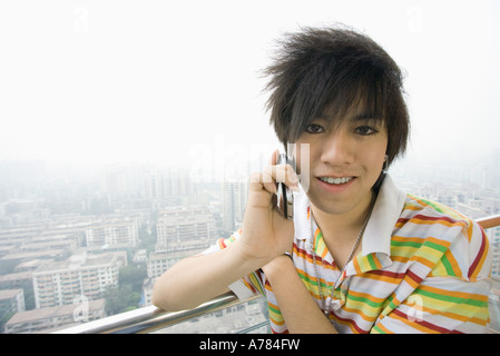 Ragazzo adolescente tramite telefono cellulare, cityscape in background Foto Stock