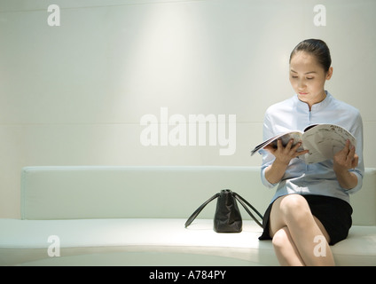 Imprenditrice seduta, rivista di lettura in sala d'attesa Foto Stock