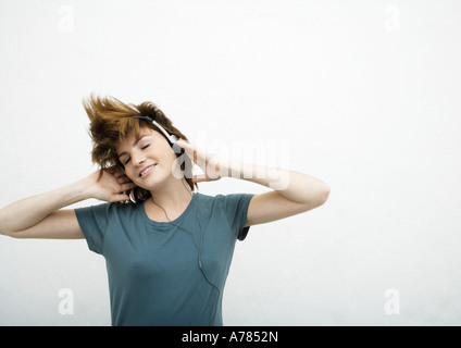 Giovane donna ascoltando le cuffie, sfondo bianco Foto Stock