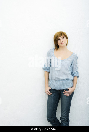 Giovane donna in piedi con i pollici in tasche Foto Stock