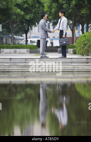 Imprenditori stringono le mani, riflessa nell'acqua Foto Stock