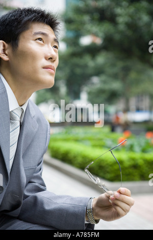 Imprenditore azienda occhiali, guardando in alto Foto Stock