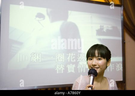 Giovane donna cantare karaoke Foto Stock