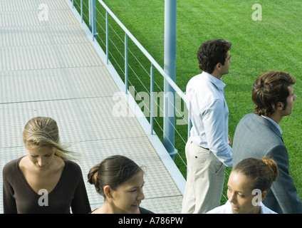 Persone in piedi e camminando sul marciapiede Foto Stock