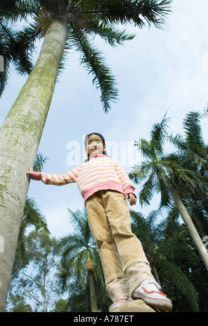 Ragazza in piedi accanto a Palm tree, basso angolo di visione Foto Stock