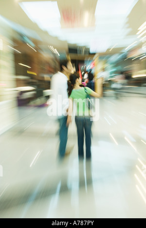 Giovane passeggiando per il centro commerciale per lo shopping, vista posteriore, a piena lunghezza e movimento sfocato Foto Stock