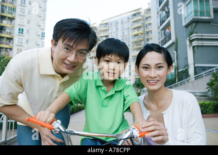 Ragazzo sulla bicicletta, tra i genitori, ritratto Foto Stock