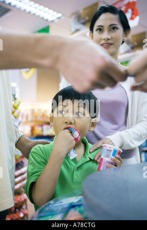 Ragazzo di mangiare snack dolce come padre paga per esso Foto Stock