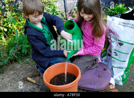 Bambini i semi di irrigazione in giardino Foto Stock